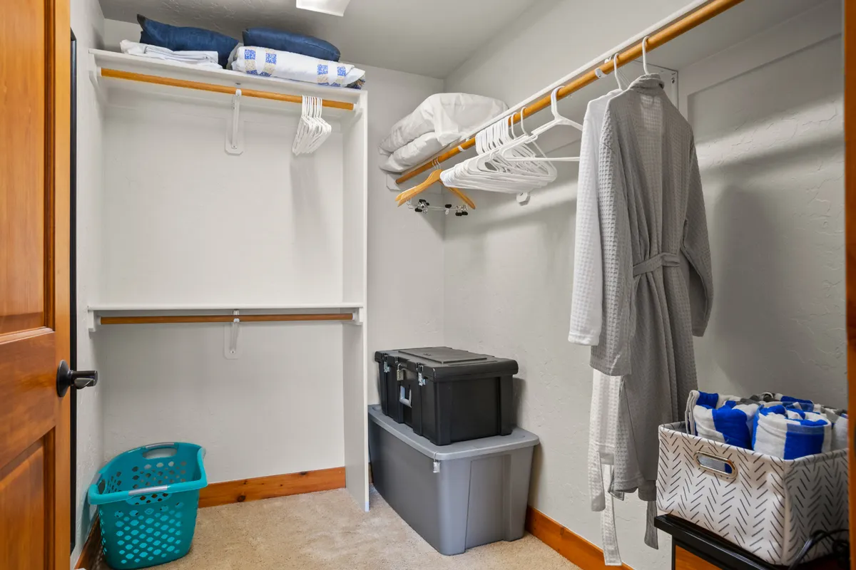 A well-organized entry or closet area featuring hanging robes, shelves with linens, and storage bins. The setup underscores ample storage and drop space for coats, boots, and adventure equipment.