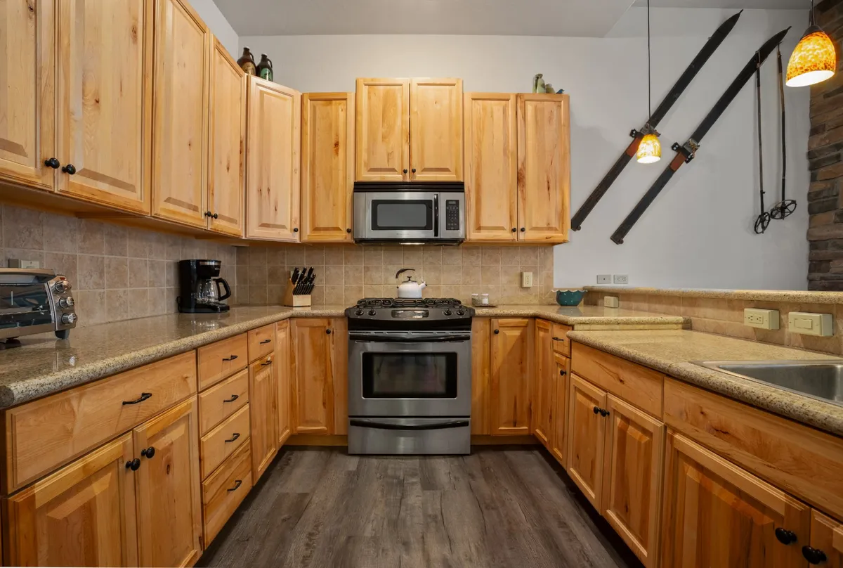 A modern kitchen equipped with wooden cabinets, stainless steel appliances, granite countertops, and decorative lighting. The breakfast bar and open flow to the rest of the living space make it ideal for culinary adventures and casual gatherings.