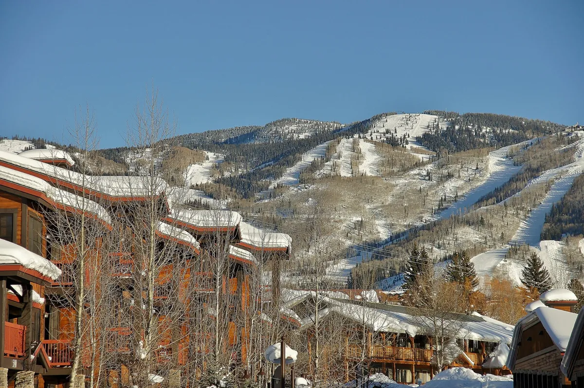 A sweeping outdoor view of snow-covered mountains, classic wooden chalets, and a clear blue sky, perfectly capturing the natural setting and local outdoor opportunities surrounding Sundance Creek 103.